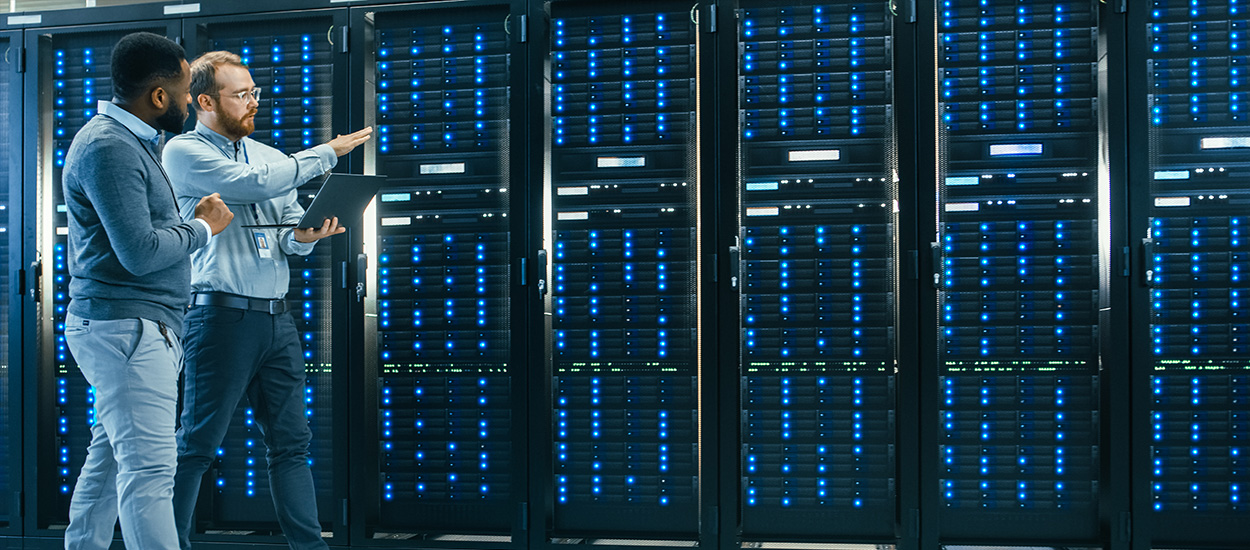 Two IT managers walk past row of servers