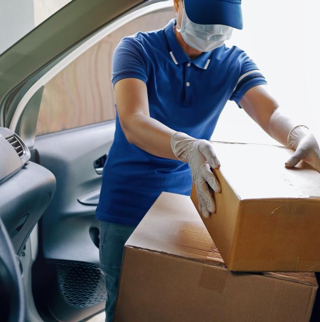 Delivery services courier during the Coronavirus COVID-19 pandemic, courier wearing medical mask and latex gloves for safety protection from virus infection working with cardboard boxes on van seat.jpg